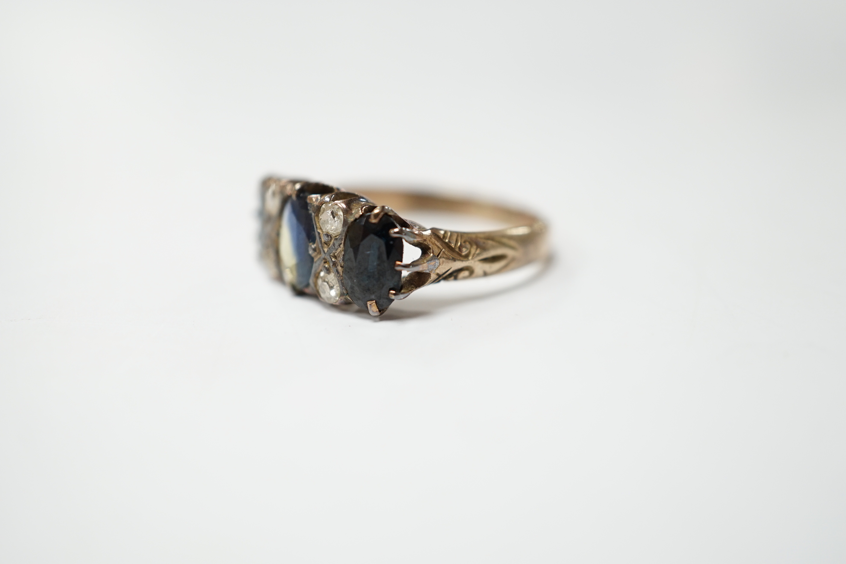 An early 20th century 18ct and graduated three stone sapphire set half hoop ring, with diamond chip spacers, size P, gross weight 3.8 grams.